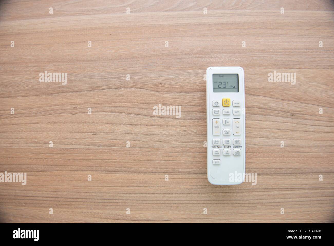 A flat lay of the remote control of an air conditioner on a wooden surface. Display showing temperature of 23º Celsius. Concept of temperature control Stock Photo