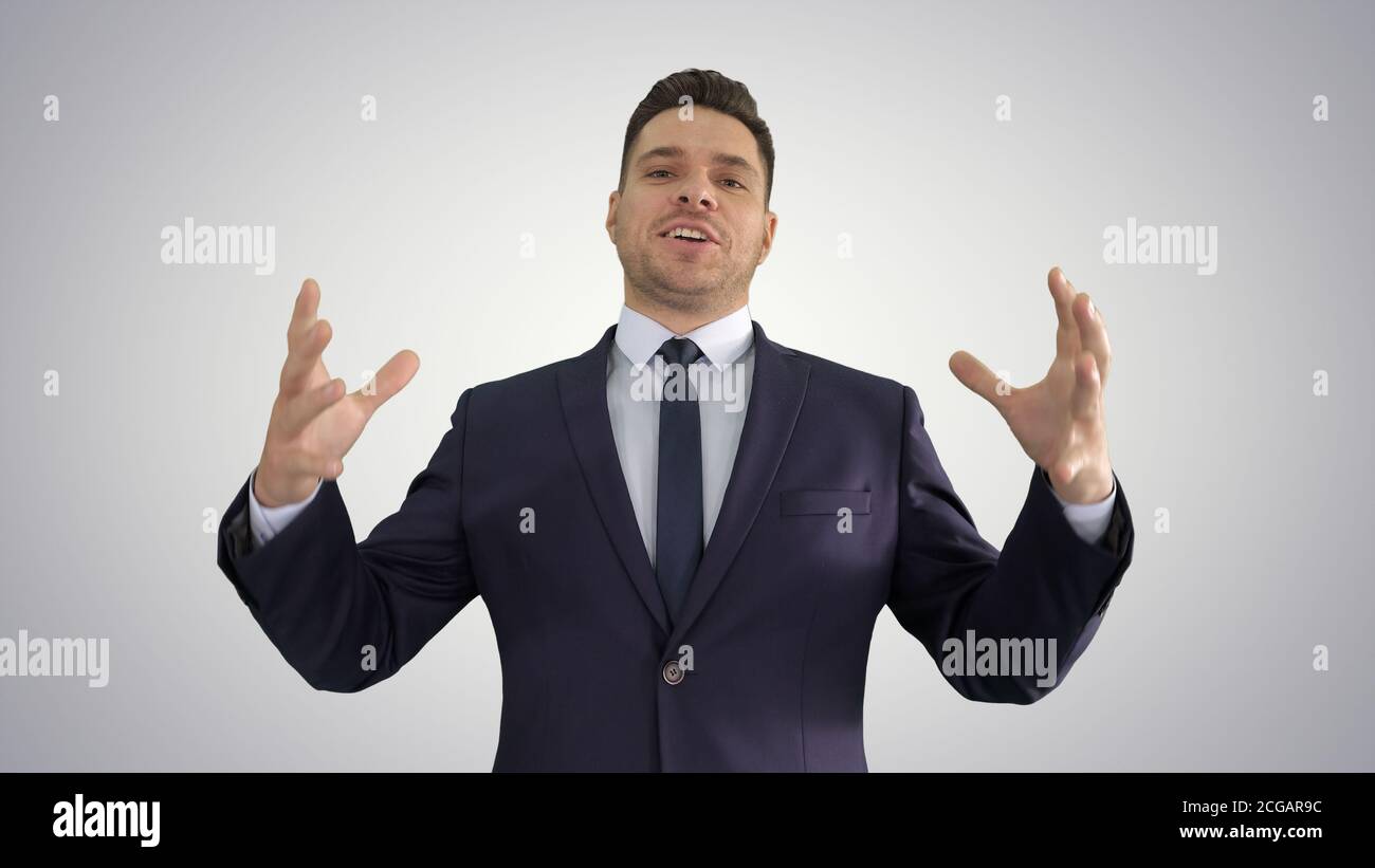 Man in formal clothes speaking to camera doing hand gestures in a very expressive and positive way on gradient background. Stock Photo