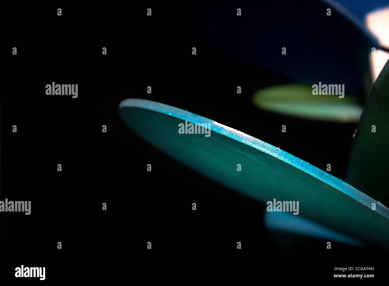 Detail of unusual aqua, green, and blue wooden objects in pitch black space Stock Photo