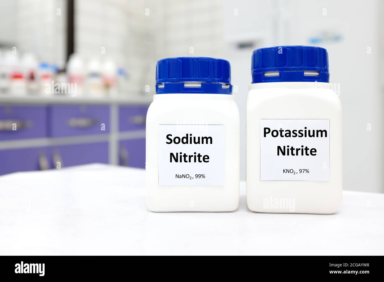Selective focus of bottles of sodium nitrite and potassium nitrite chemical preservative. White laboratory background with copy space. Stock Photo