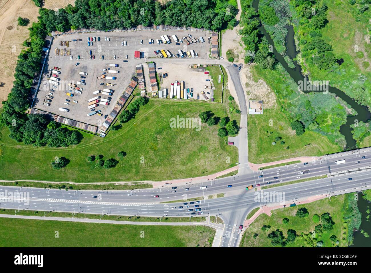 aerial drone view of a suburban road with intersection and parking lot with trucks Stock Photo