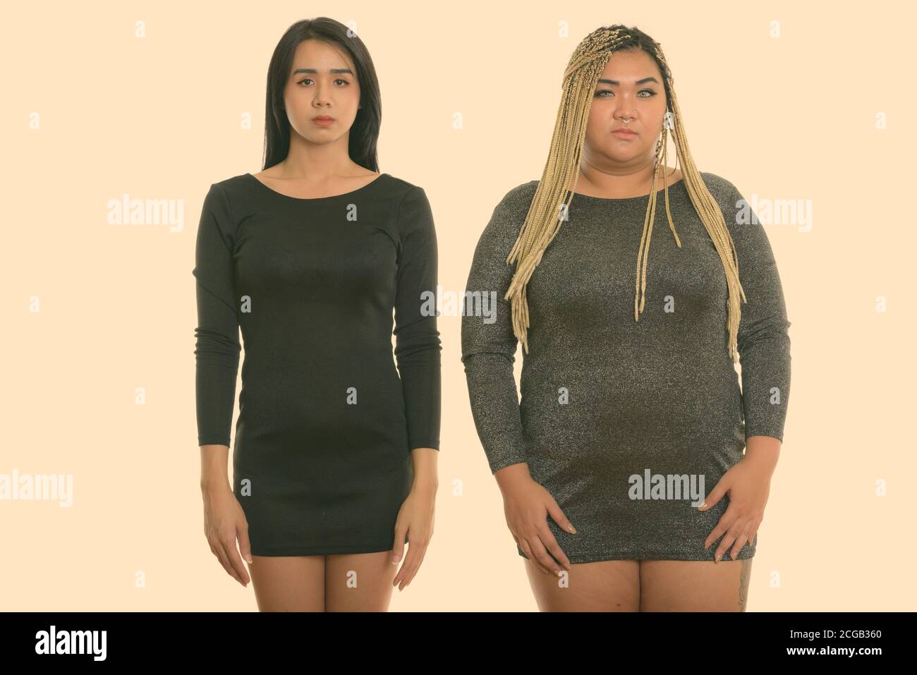 Studio shot of young Asian transgender woman and fat Asian woman standing together Stock Photo