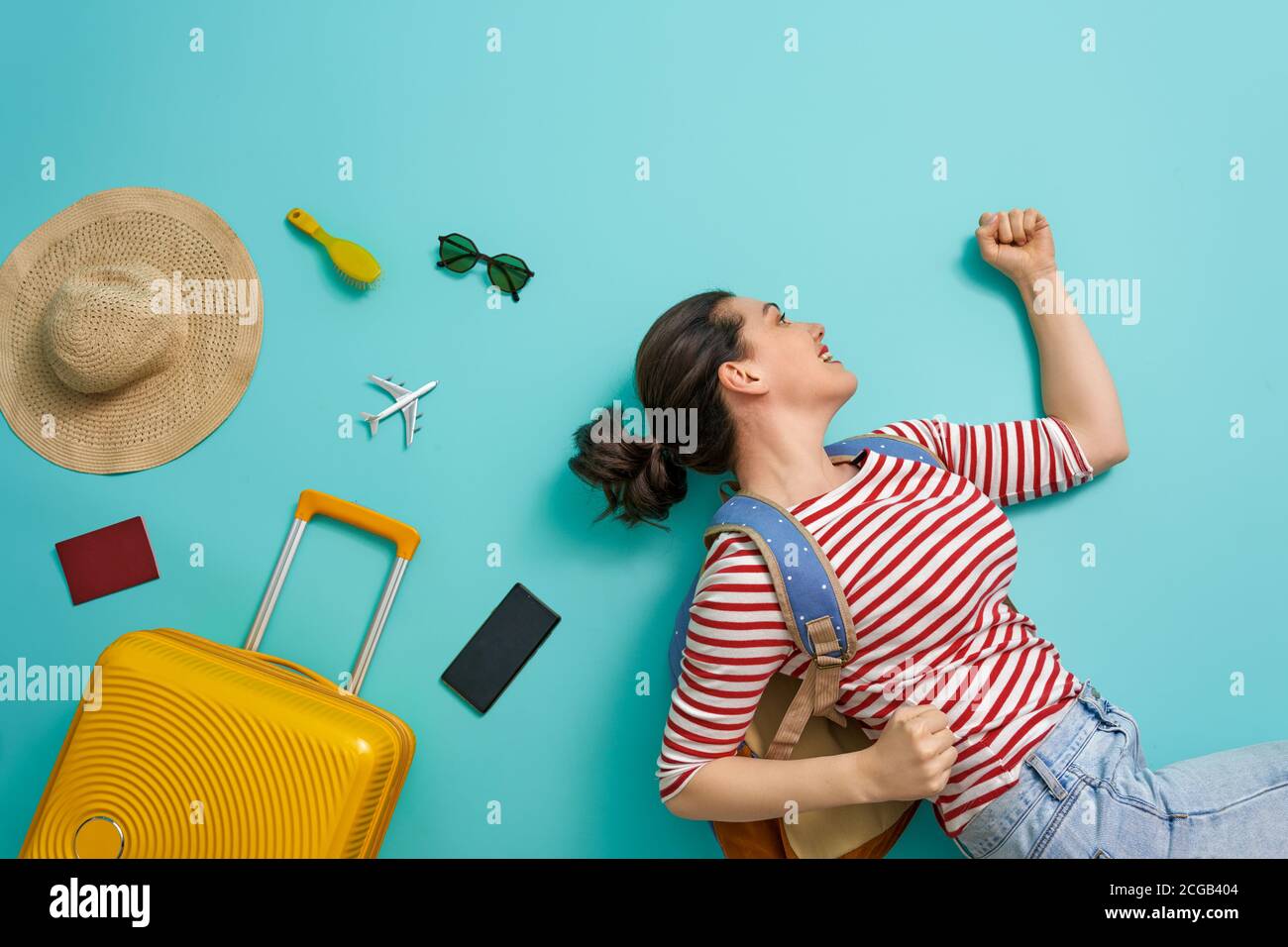 Go on an adventure! Happy woman going traveling. Young person on color teal background. Stock Photo