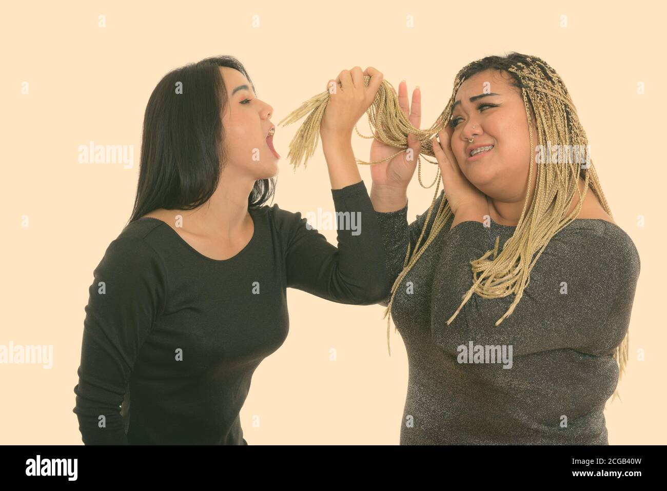 Young Asian transgender woman eating the hair of fat Asian woman Stock Photo