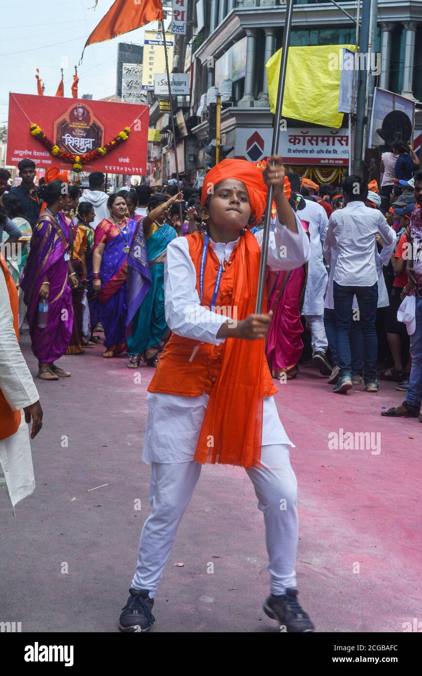 Pune, India - September 4, 2017: A small girl looking aggressive and is passionately dancing with a flag on the occasion of ganpati visarjan festival Stock Photo