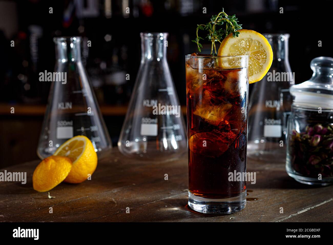 A brown cocktail or lemonade with Cola stands on the counter of a dark bar. Stock Photo