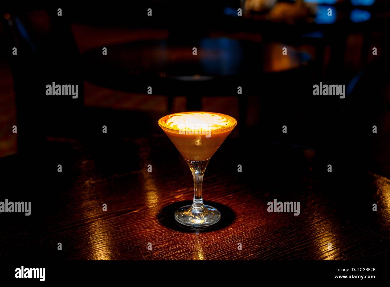 Coffee cocktail with white foam on the counter of a dark bar. Stock Photo