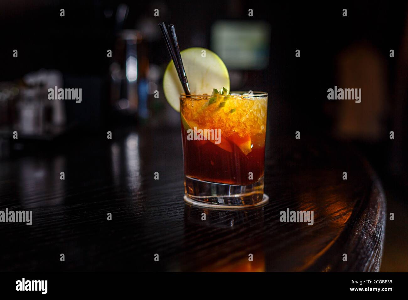 A cocktail with whiskey or cognac or Cola in a highball glass is on the counter of a dark bar. Stock Photo
