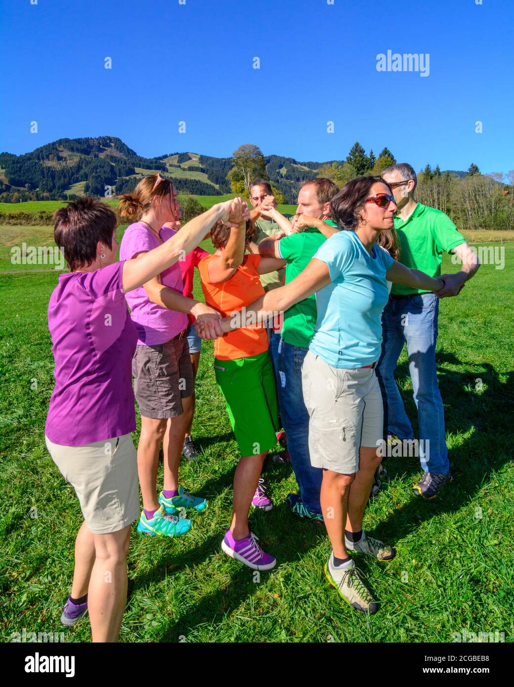 Eine Gruppe bei einer Teambuilding-Übung - das Zusammenspiel im Team bringt letztlich den Erfolg, auch und vor allem beim Lösen schwieriger Aufgaben - Stock Photo