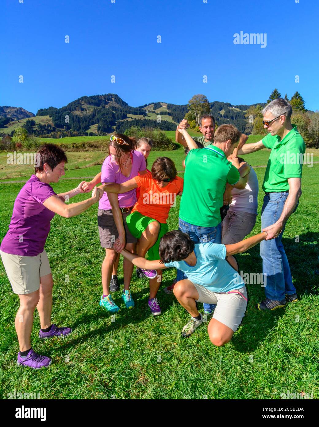 Eine Gruppe bei einer Teambuilding-Übung - das Zusammenspiel im Team bringt letztlich den Erfolg, auch und vor allem beim Lösen schwieriger Aufgaben - Stock Photo