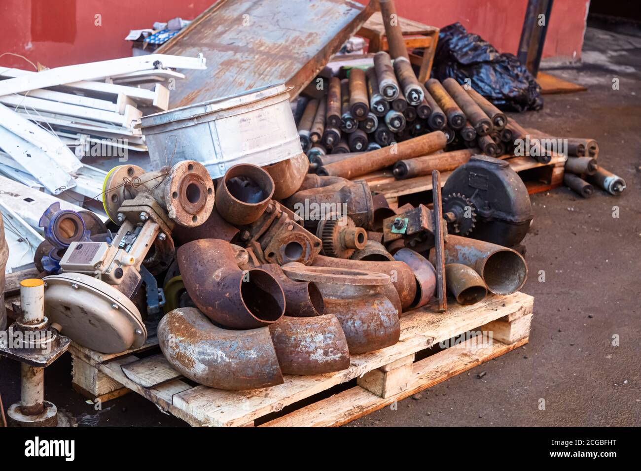Scraps of old rusty pipes and other old parts lie on the ground. Stock Photo