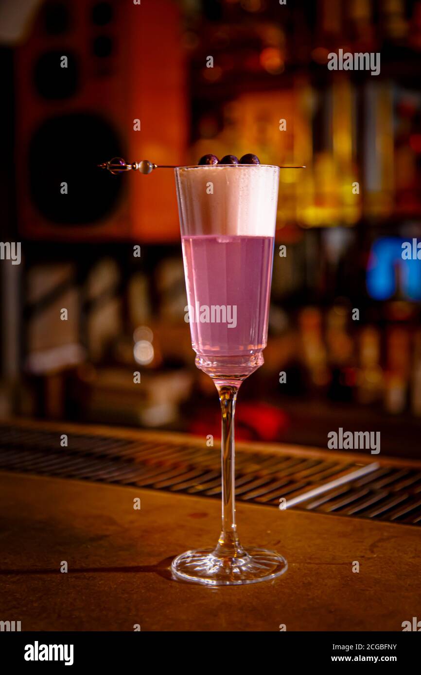 A purple Sauer cocktail in a tall glass with foam stands on the bar Stock Photo