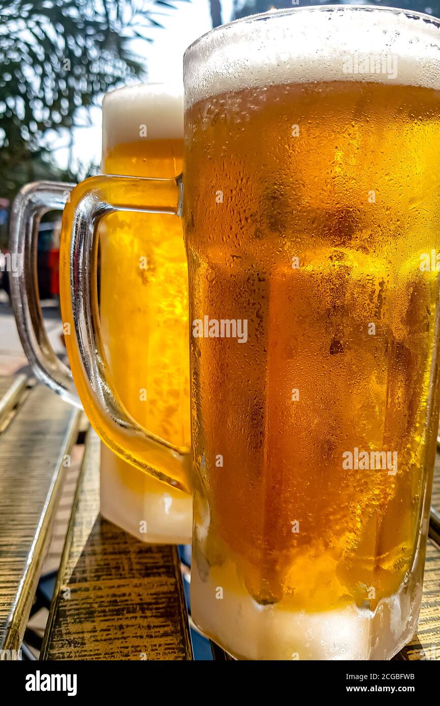 A steaming mug of cold beer on the table of a summer cafe in the southern city. Stock Photo