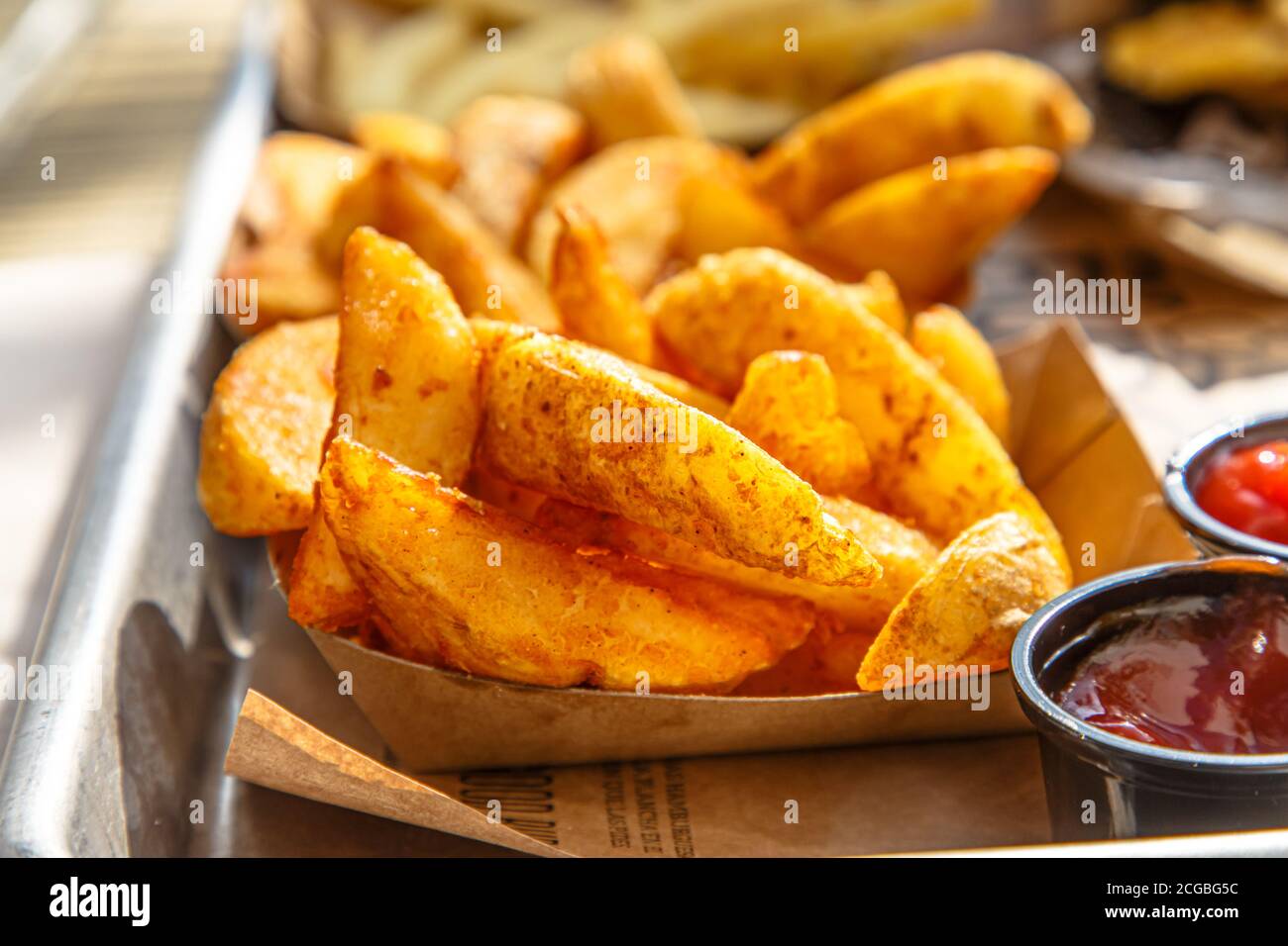 Burgers, potatoes, ketchup and mugs of beer on the table of a street cafe. Stock Photo