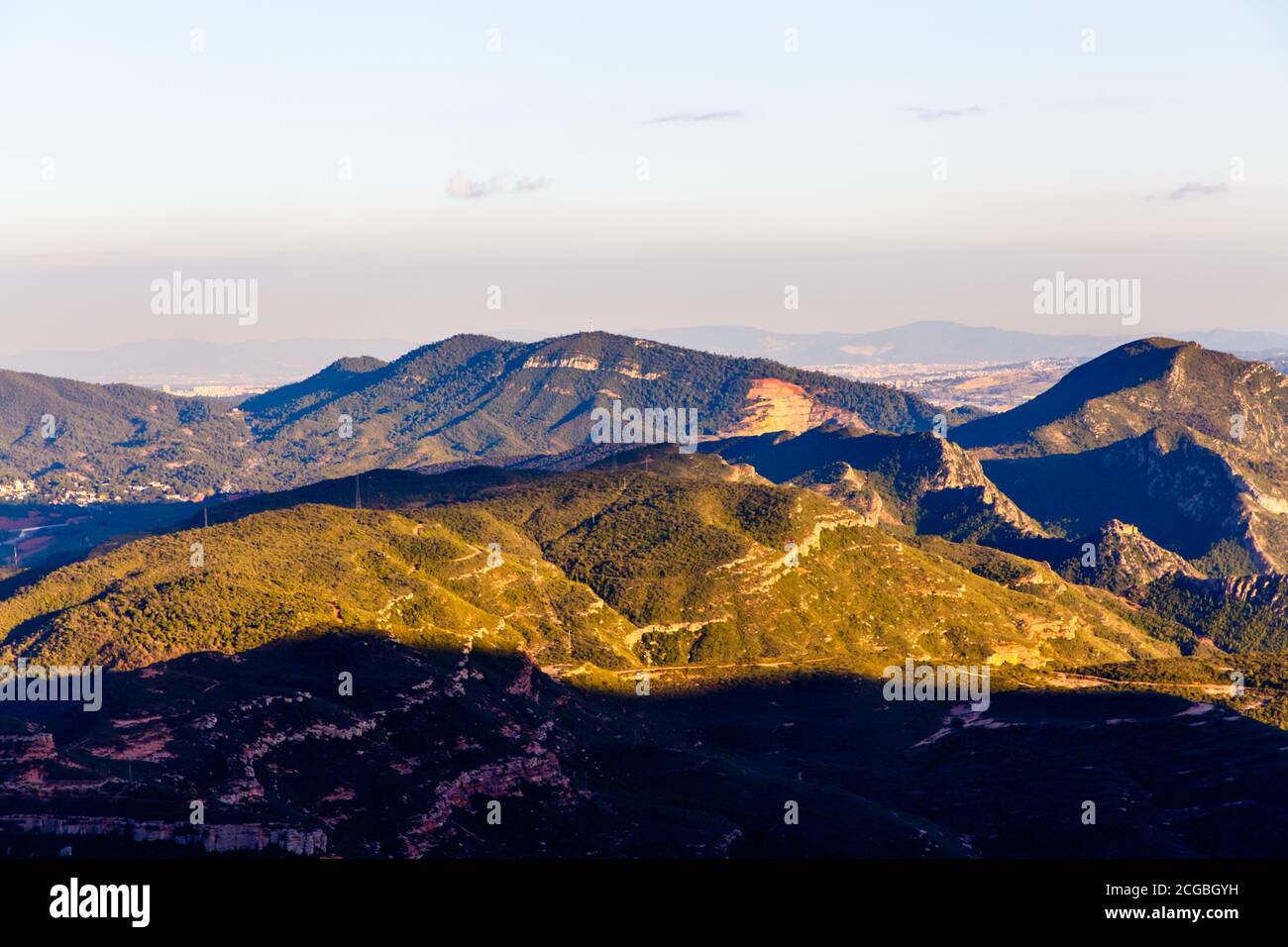 Evening in the mountains, the sun illuminates the peaks, and the lowlands are already in the shade. Spain Stock Photo