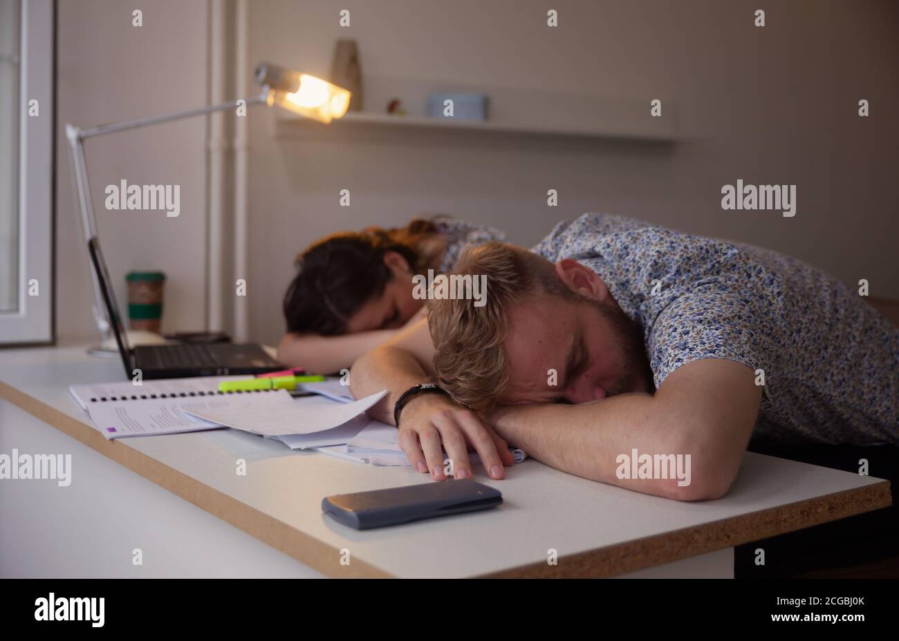 two students or coworkers, sleeping on table, exsuasted from studying. Stock Photo
