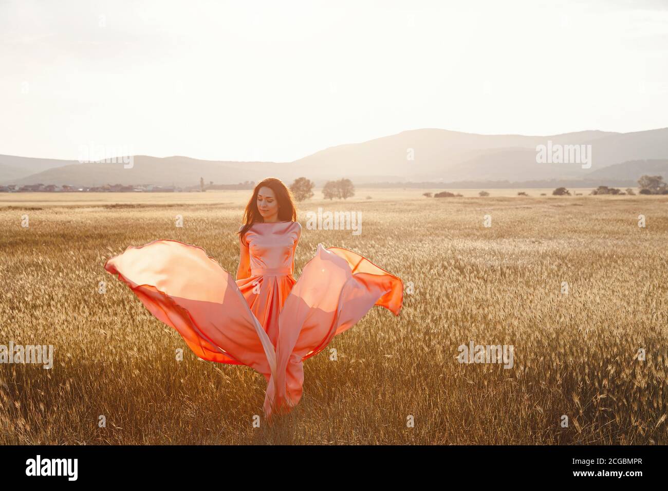 girl dancing in a field in a beautiful pink dress at sunset. ideal for ...
