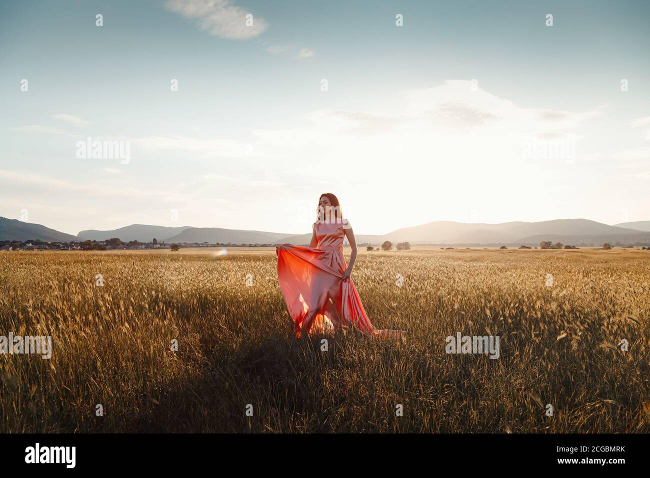 girl dancing in a field in a beautiful pink dress at sunset. ideal for ...