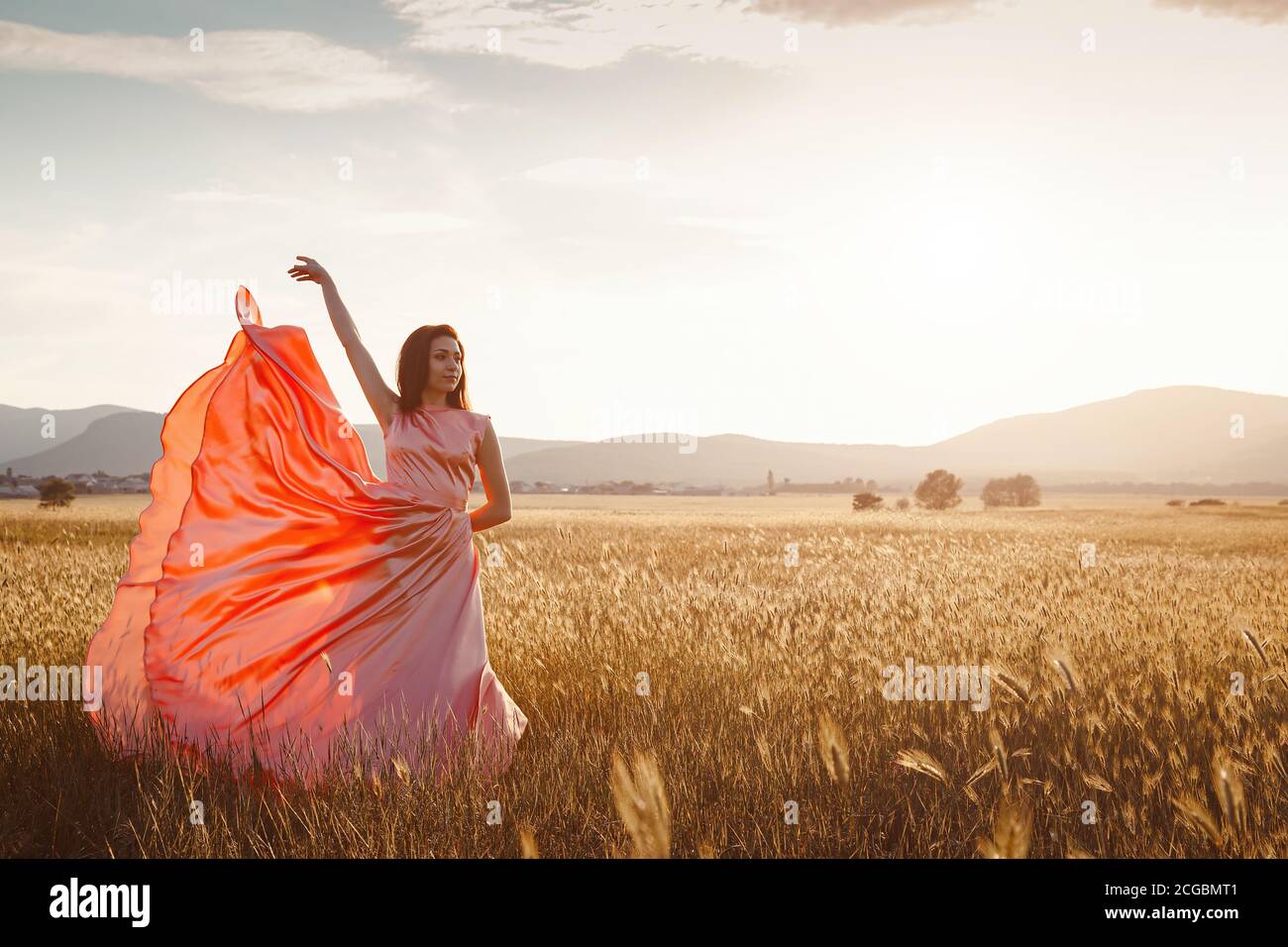 girl dancing in a field in a beautiful pink dress at sunset. ideal for ...