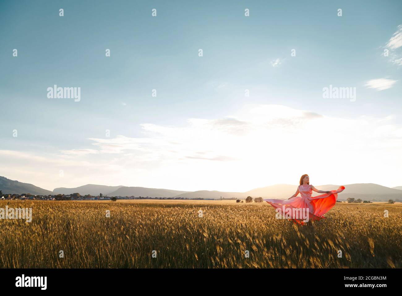 girl dancing in a field in a beautiful pink dress at sunset. ideal for ...