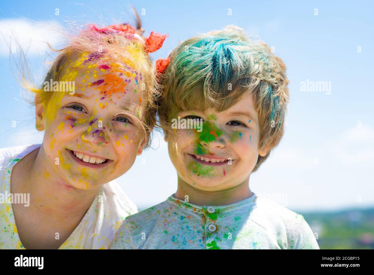 Smiling little kids portrait. Painted faces of funny kids. Children holi festival of colors. Little boy and girl plays with colors. Stock Photo