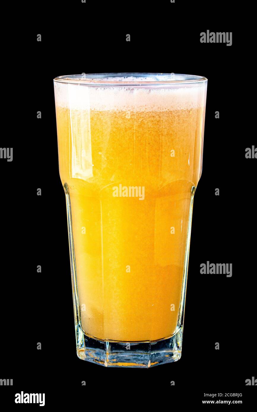 Yellow smoothie (orange, mandarin) in a large glass glass on a black background, isolated. Stock Photo