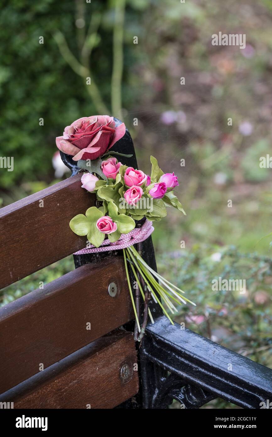 A bouquet of plastic roses tied to a bench. Stock Photo