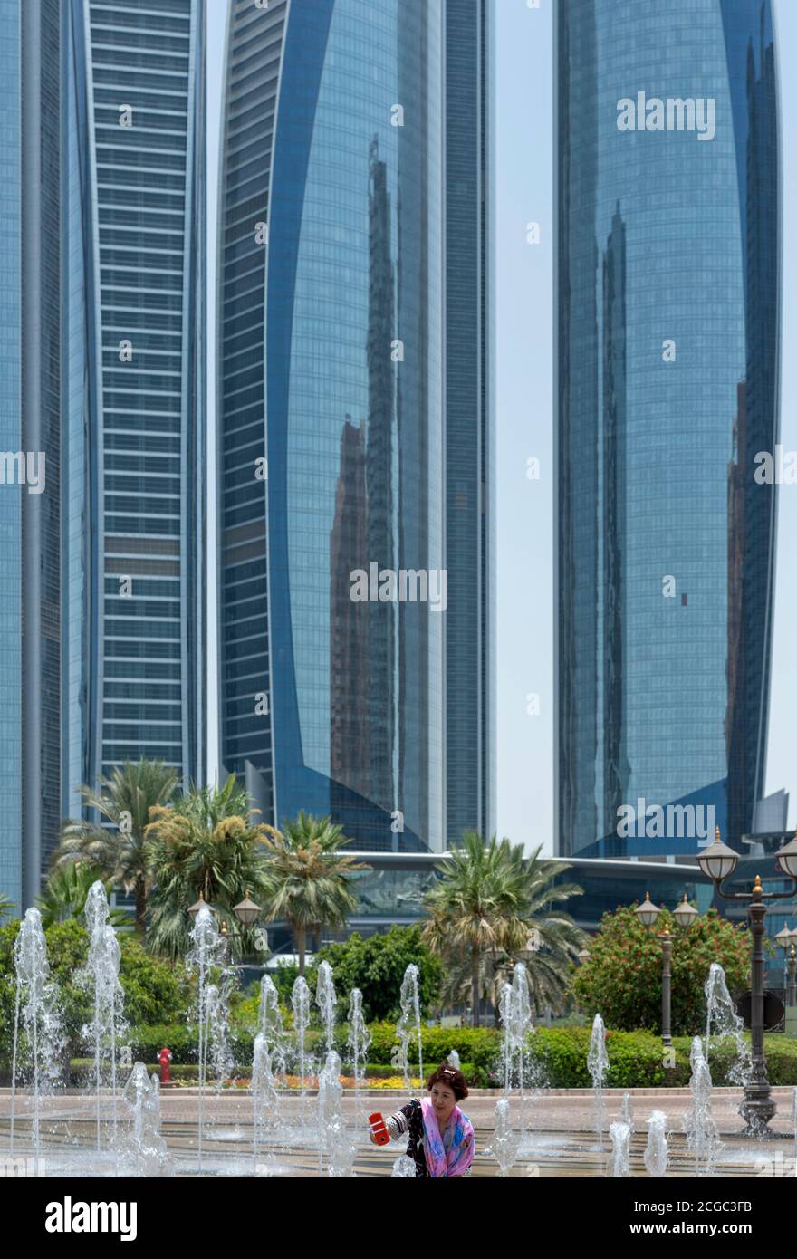 A tourist taking a selfie in the water fountain feature in front of the Etihad Towers, Abu Dhabi. Stock Photo