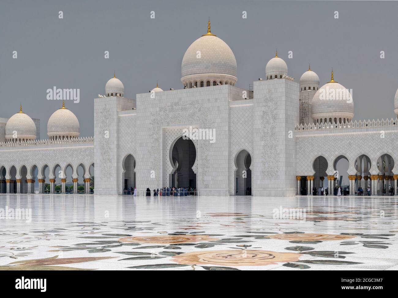 A day shot of the Sheikh Zayed Grand Mosque, Abu Dhabi entrance and central inner courtyard, marble floor with floral design, domes, arches, columns and tourists. Mosque completed 2007. Stock Photo