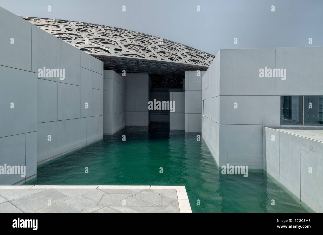 A exterior shot of the Louvre Abu Dhabi's facade which includes water, the hi-tech roof and white wall. Opened November 2017. Stock Photo