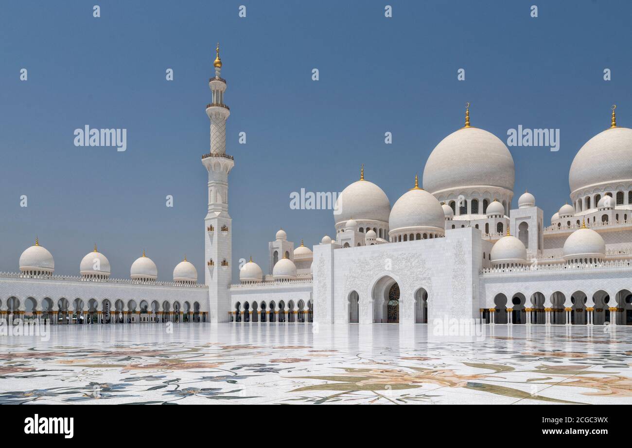 A day shot of the  Sheikh Zayed Grand Mosque, Abu Dhabi central inner courtyard with two workers polishing the marble floor. The architectural features includes domes, the main dome, central arches, columns and the floral marble floor. Mosque completed 2007. Stock Photo