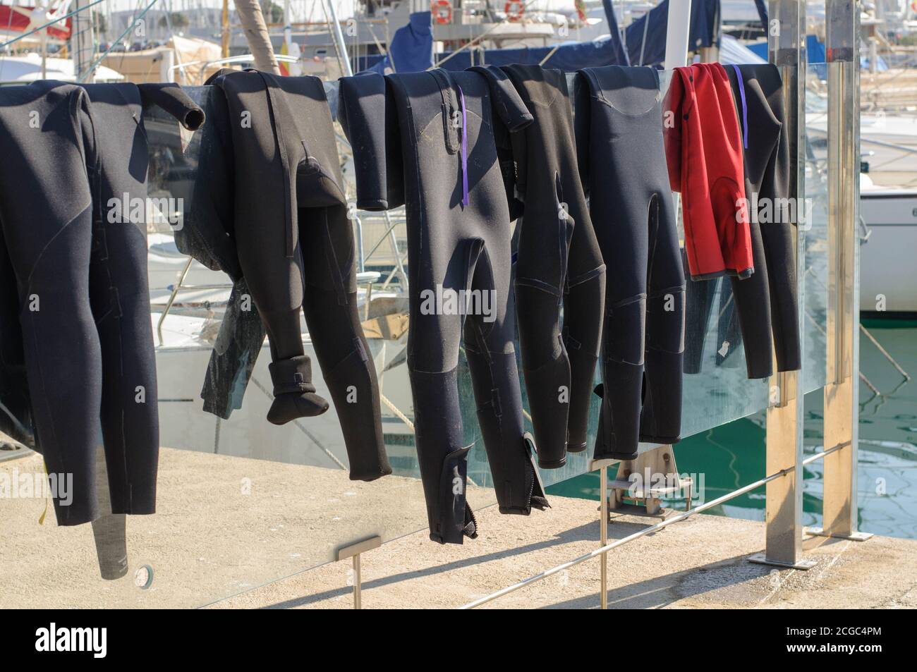 Surf suits dry in the sun on a glass fence Stock Photo Alamy