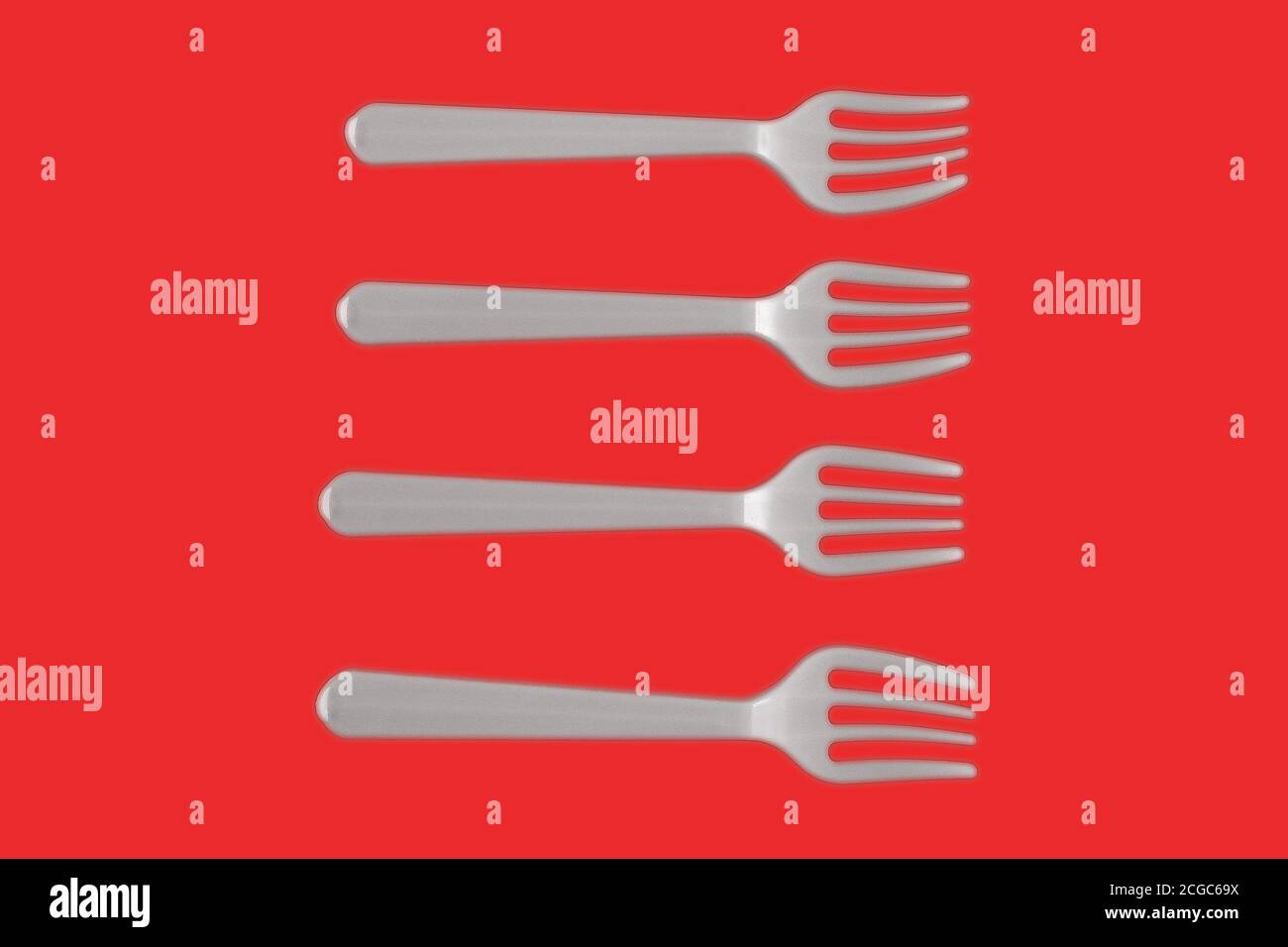 four plastic white forks on a red background Stock Photo