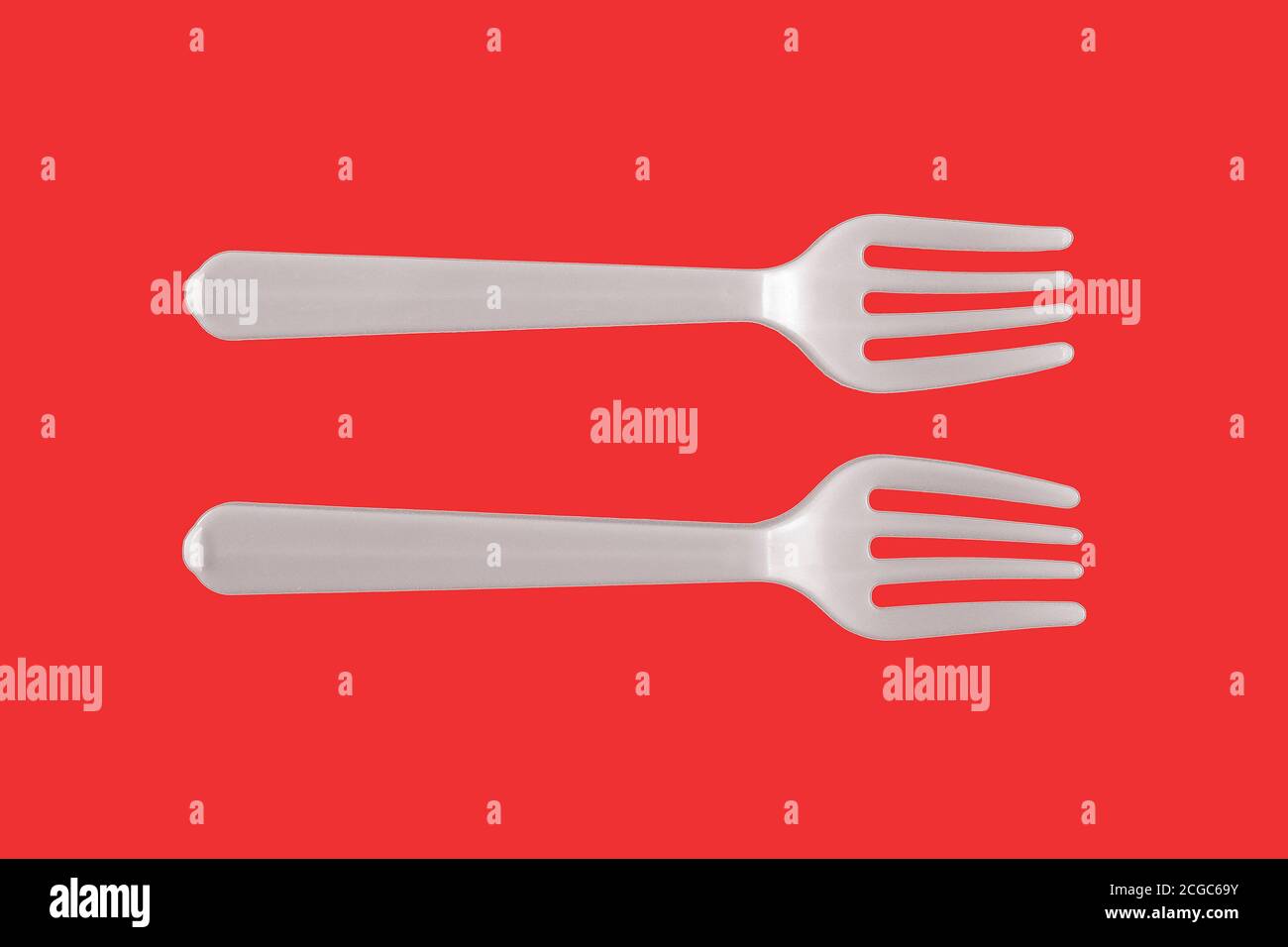 Two plastic white forks on a red background Stock Photo