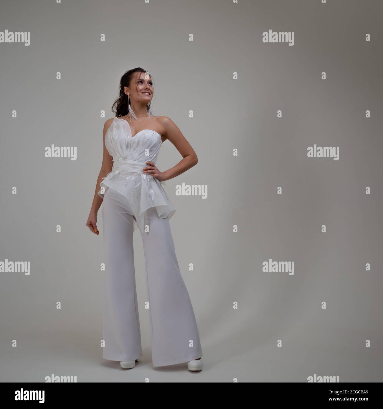 A young brunette woman in a stylish and elegant pantsuit. Wedding suit with trousers, modern style. Evening equipment, outfit for the celebration. Stock Photo
