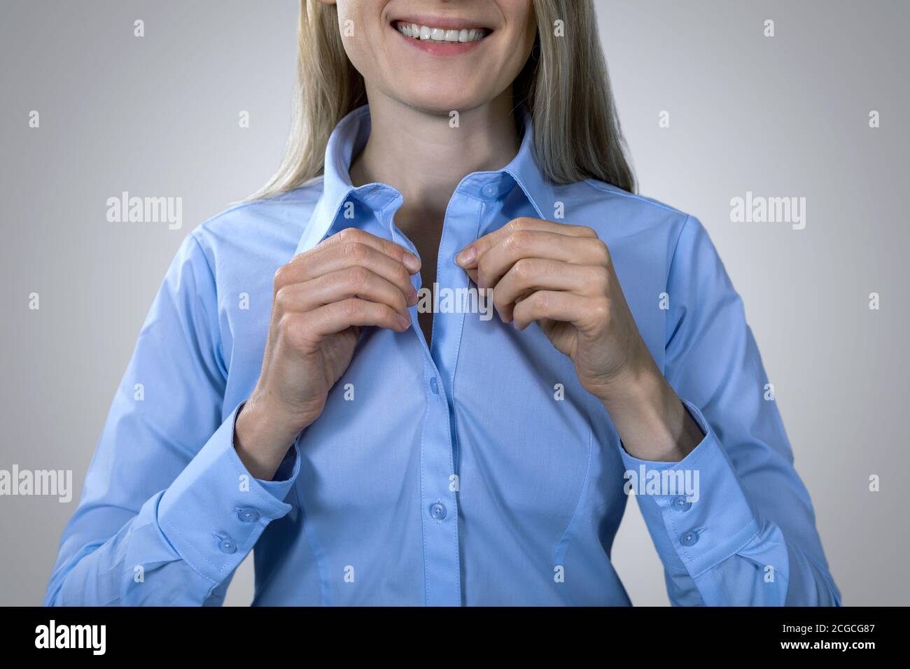 business formal dress code - smiling woman buttoning blue blouse Stock Photo