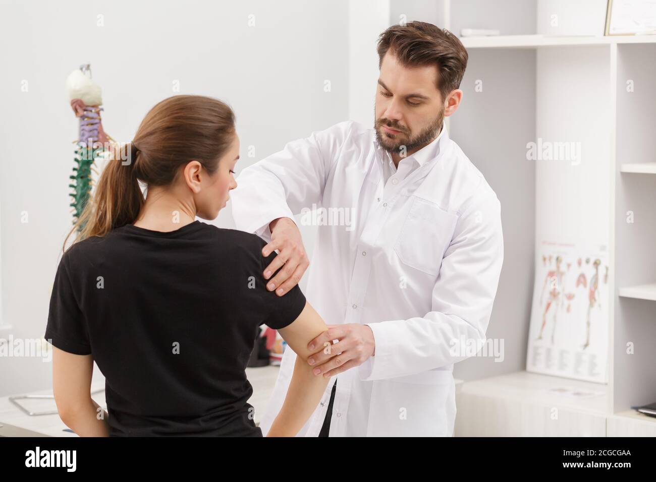 Male Doctor Examining Female Patient Suffering From Elbow Pain Medical Exam Chiropractic