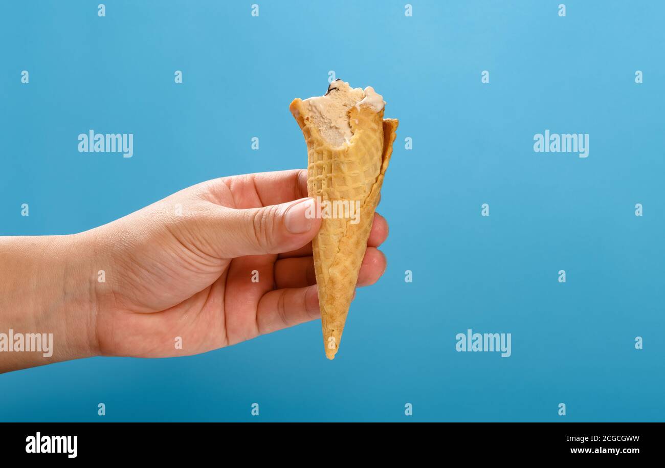 Hand Holding A Half Eaten Milk Tea Flavor Ice Cream Cone On A Blue Background Stock Photo Alamy