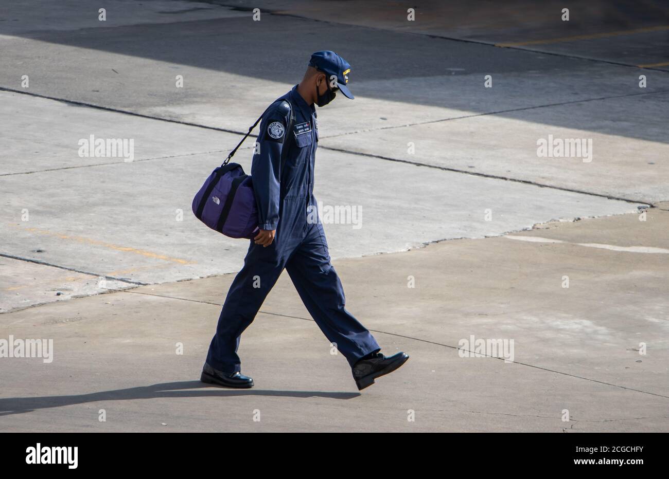 SAMUT PRAKAN, THAILAND, JUN 26 2020, A man in a blue overalls with the HTMS Sichang emblem walks on the street. Stock Photo
