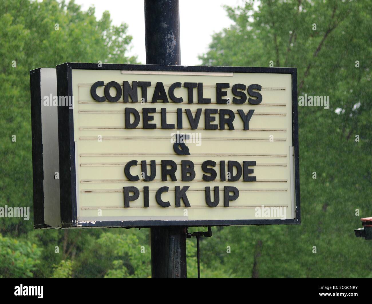 Business sign during the Summer of 2020 Covid-19 era says they offer Contactless Delivery and Curbside Pick Up to reopen safely and protect customers Stock Photo