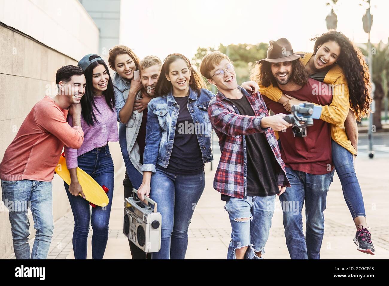 Happy young friends filming video with gimbal mobile smartphone outdoor - Millennial trendy people having fun with new technology social media apps Stock Photo