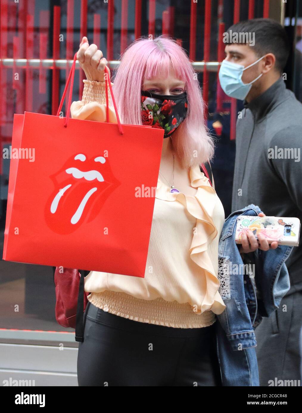 London, UK. 09th Sep, 2020. A lady with pink hair wearing a facemask holds her purchases inside a Rolling Stones logo bag outside the new store.The official Rolling Stones store, RS No. 9 opens in London's Carnaby Street. Credit: SOPA Images Limited/Alamy Live News Stock Photo