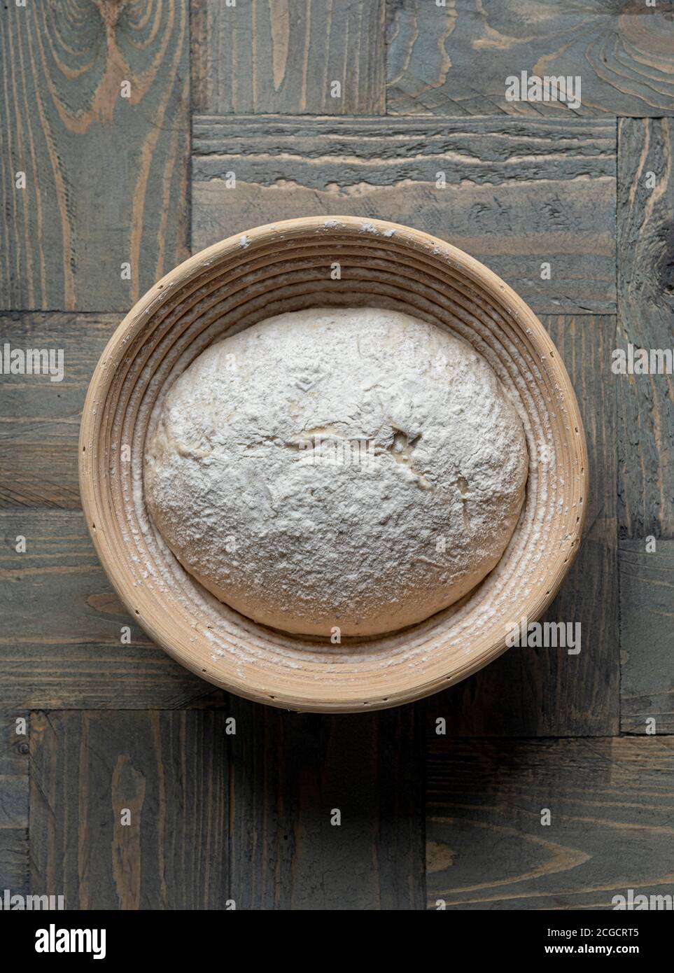 Sourdough bread dough in wicker banneton proving basket on wooden background Stock Photo