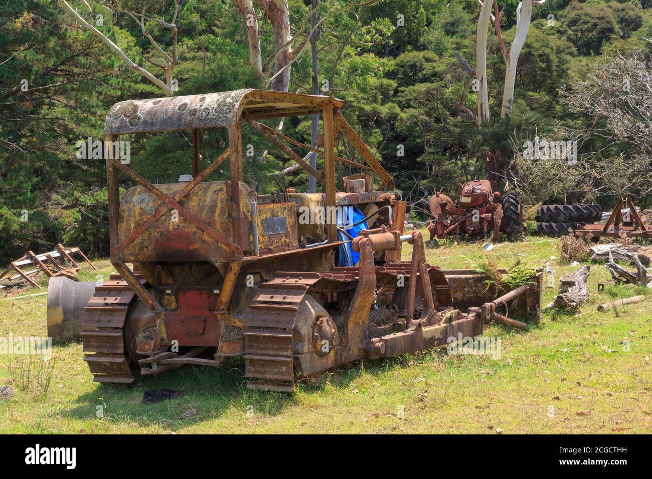 An old, rusty bulldozer, abandoned on a farm with other machinery Stock Photo