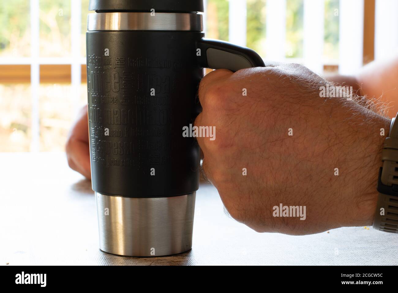 hands of a men ist holding a thermos coffee mug Stock Photo