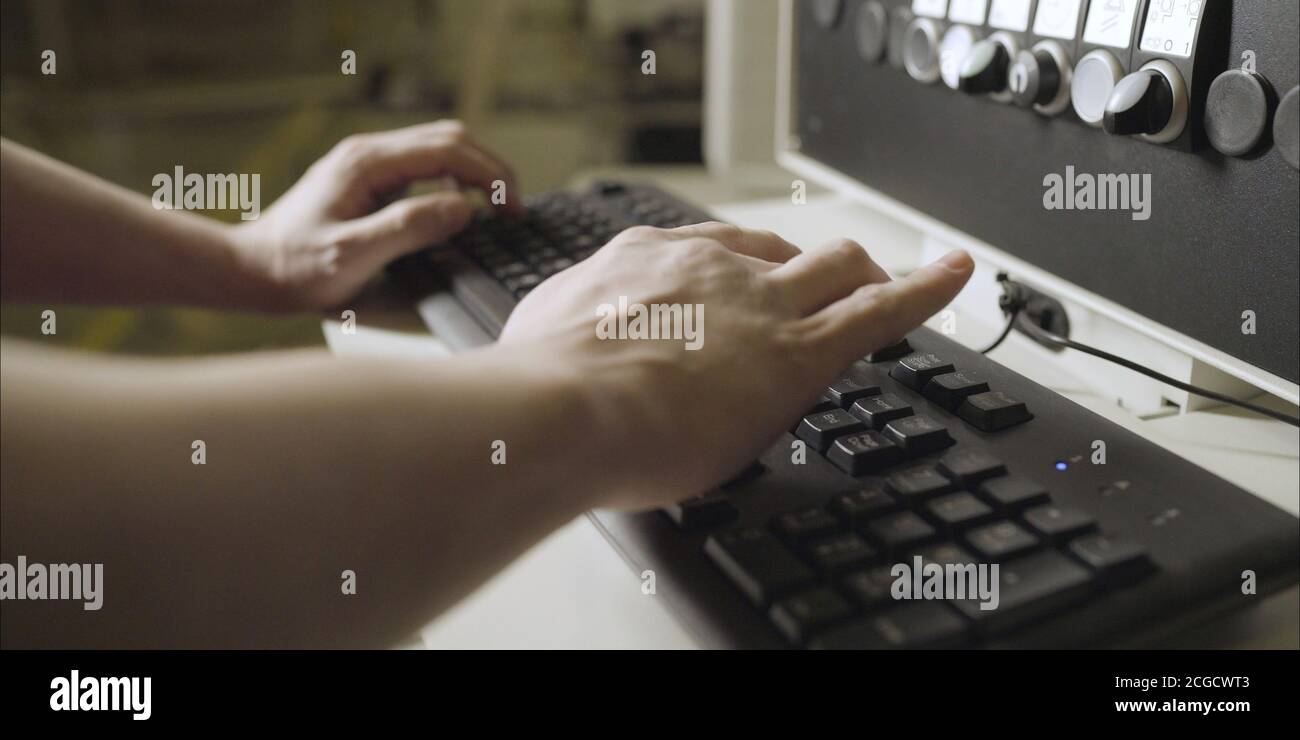 The worker types the machine parameter on the keyboard. Stock Photo