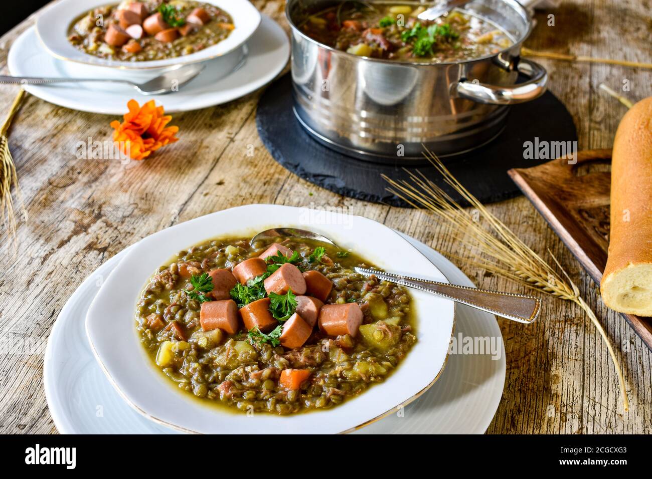 hearty lentil stew with sausages such as hot dogs on a white soup plate served hot on a table Stock Photo