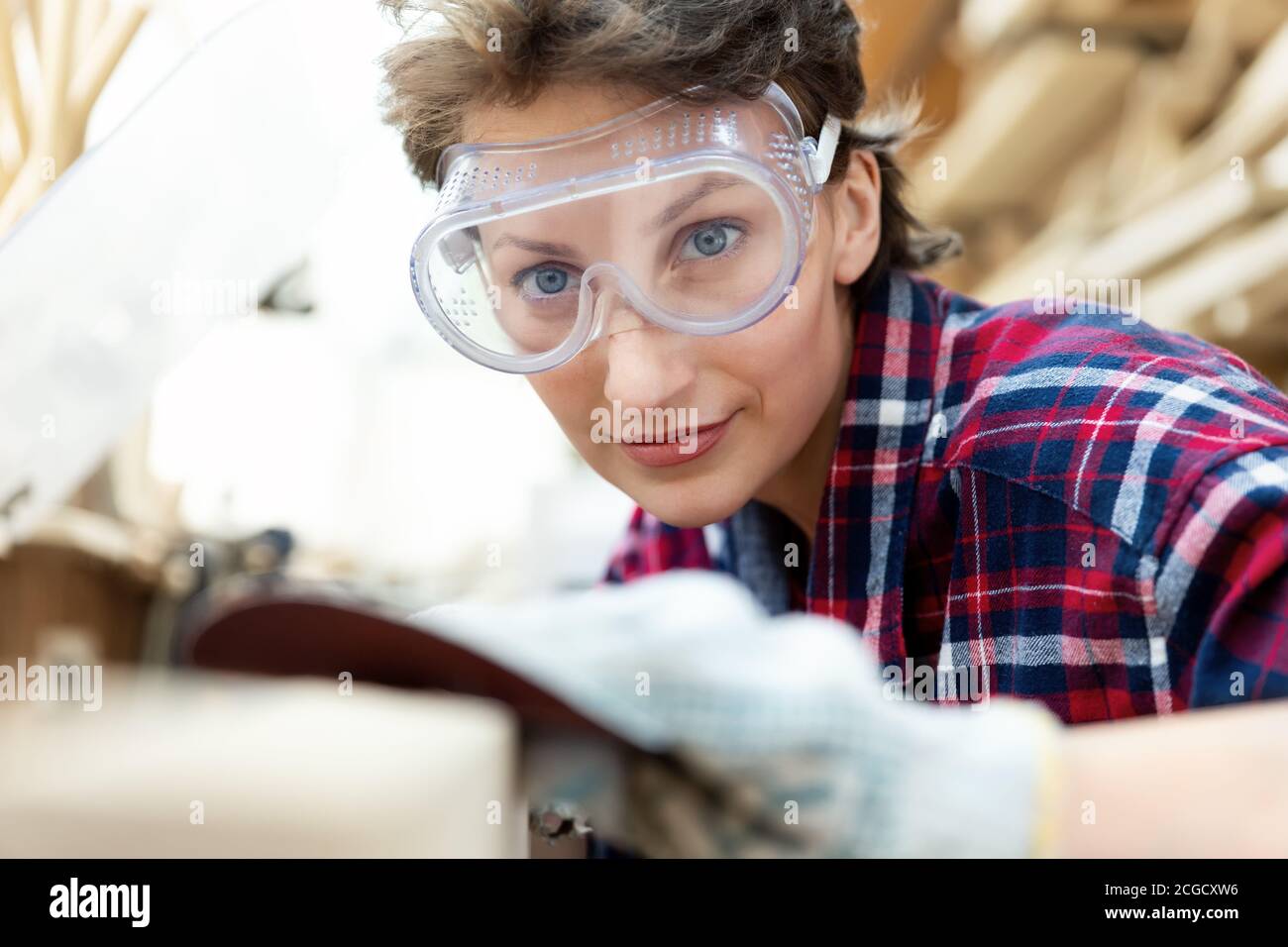 Young professional beautiful 3040 female carpenter looking and sanding