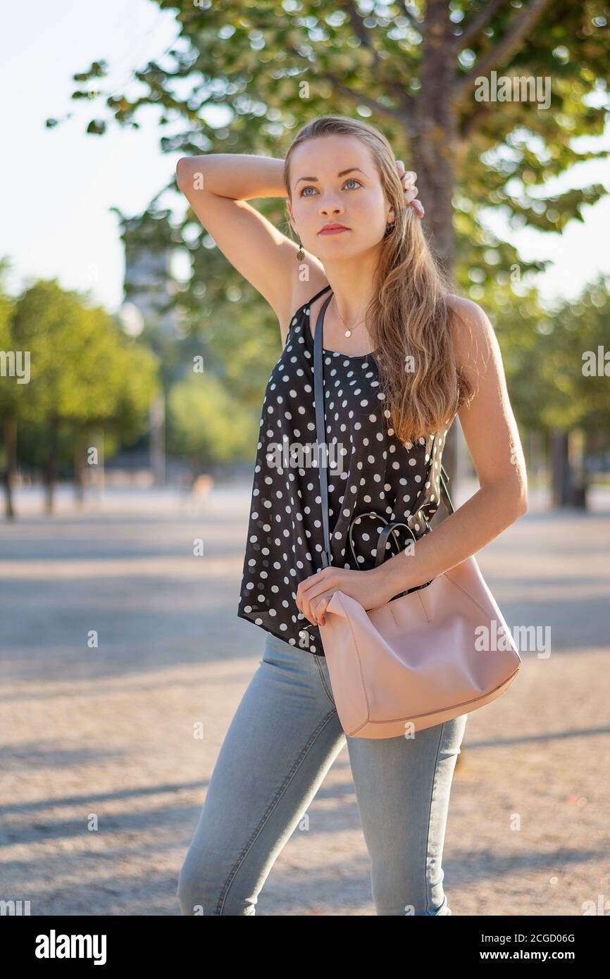 Summer in the city. A young woman with a handbag at sunrise. Urban background. Stock Photo
