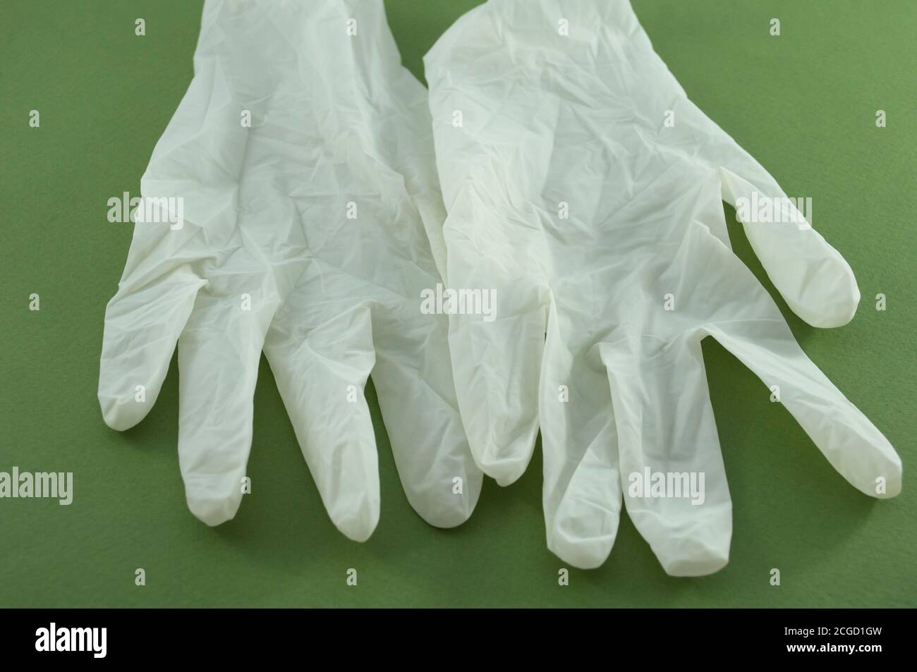 The photo shows white latex survey non-sterile powdered gloves on a green background close up Stock Photo